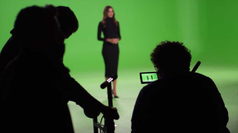 A camera dolly with a broadcast camera on top recording a green screet set for virtual production