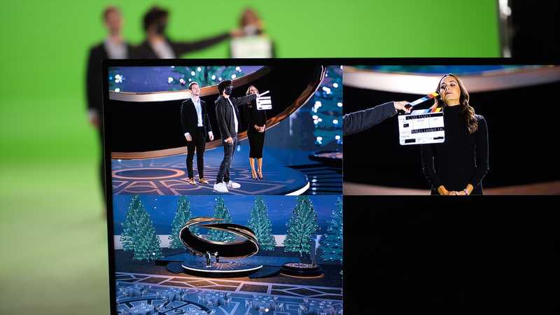 Green screen production set with two actors standing, a clapperboard and a screen showing multiple virtual environments for film production in Mexico.